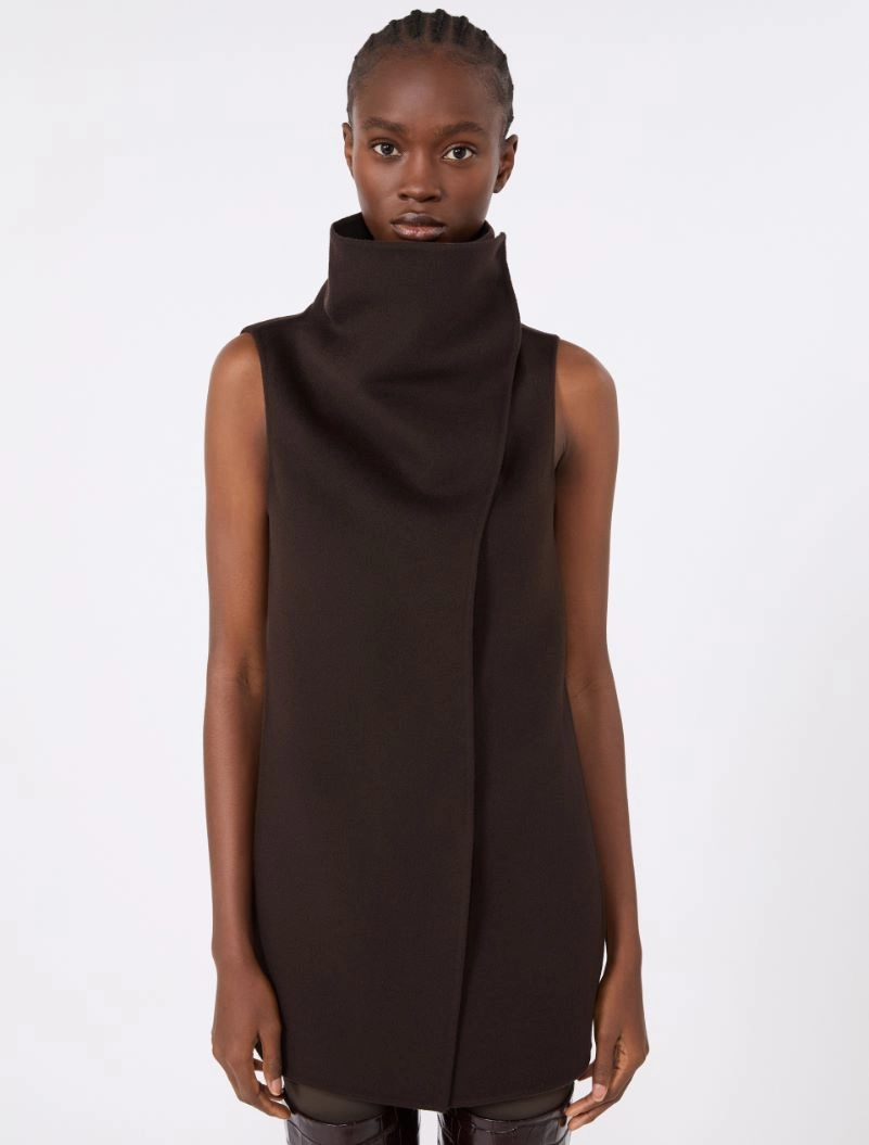 IMG_3717 - New Trend Model wearing a dark brown sleeveless high-neck tunic dress with a structured draped collar, standing against a light background.