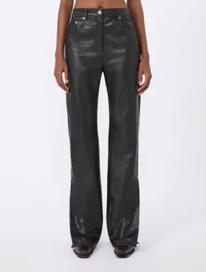 Front view of a person wearing black high-waisted, wide-leg leather-look pants and brown shoes, standing against a white background.