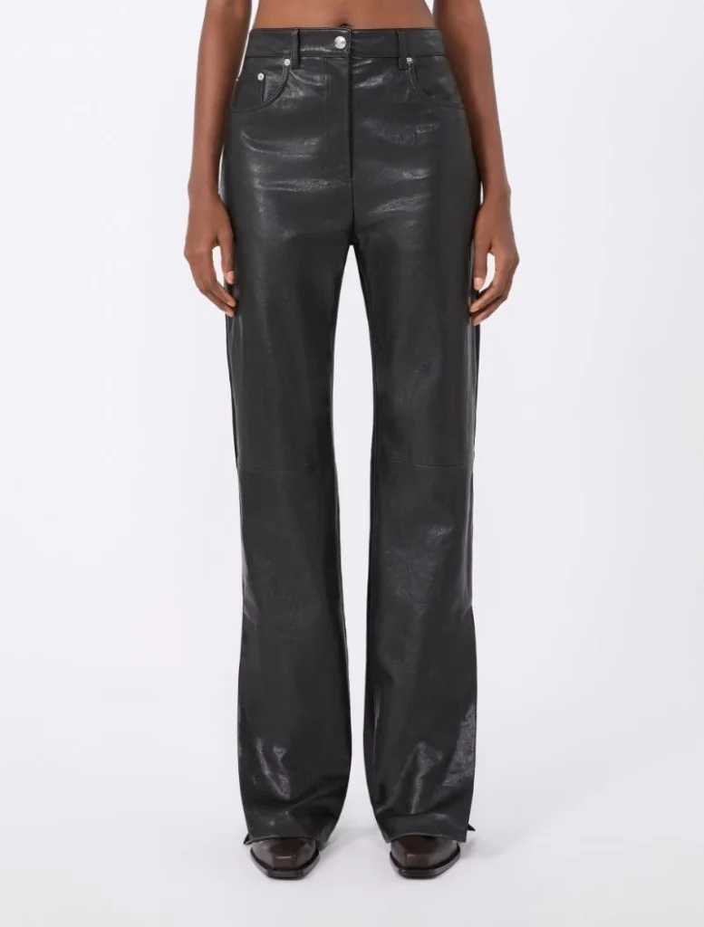 Front view of a person wearing black high-waisted, wide-leg leather-look pants and brown shoes, standing against a white background.