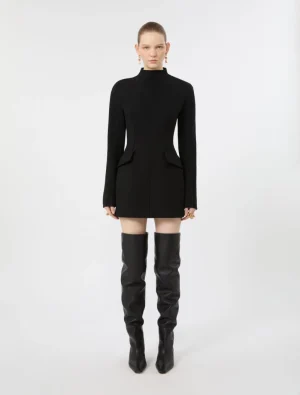 Model in a black fitted mini dress with a high neckline and structured hip pockets, paired with black over-the-knee boots.