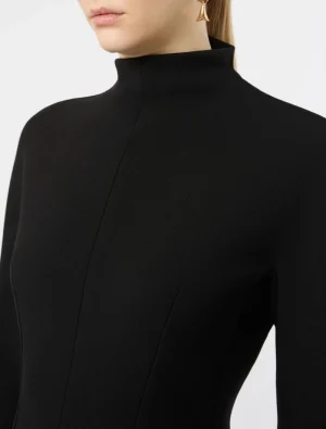 Close-up of a black high-neck dress with structured seams and a gold earring visible at the neck area