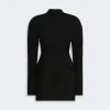 Black tailored long-sleeve coat with a high neckline and front seam, featuring flap pockets at the hips and a clean, minimalist silhouette.