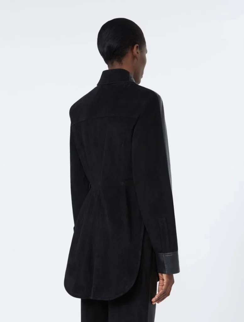 Back view of a person wearing a long black belted coat with a curved hem, seen from behind.