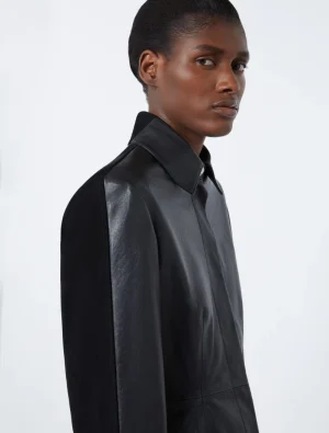 Side profile of a person with short hair wearing a black leather shirt against a pale background.