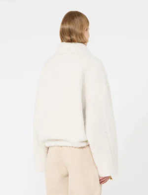 Back view of a person wearing a white fluffy teddy coat and beige trousers.