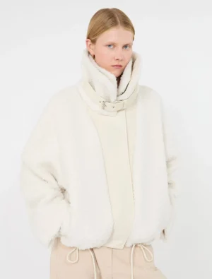Model wearing an oversized white fleece jacket with a high collar and belt against a white backdrop.