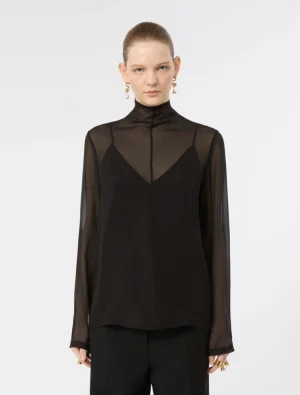 Model wearing a black sheer blouse with a high neck and an inner black top, paired with black pants against a white background.