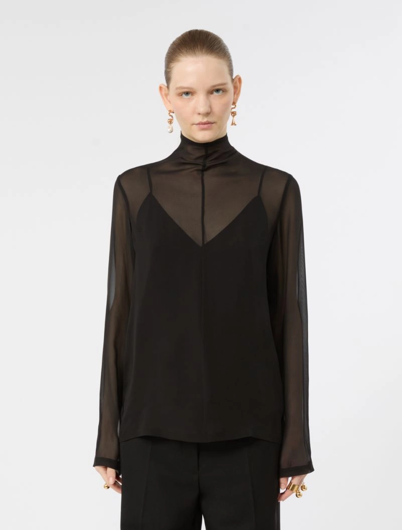 IMG_3774 - New Trend Model wearing a black sheer blouse with a high neck and an inner black top, paired with black pants against a white background.
