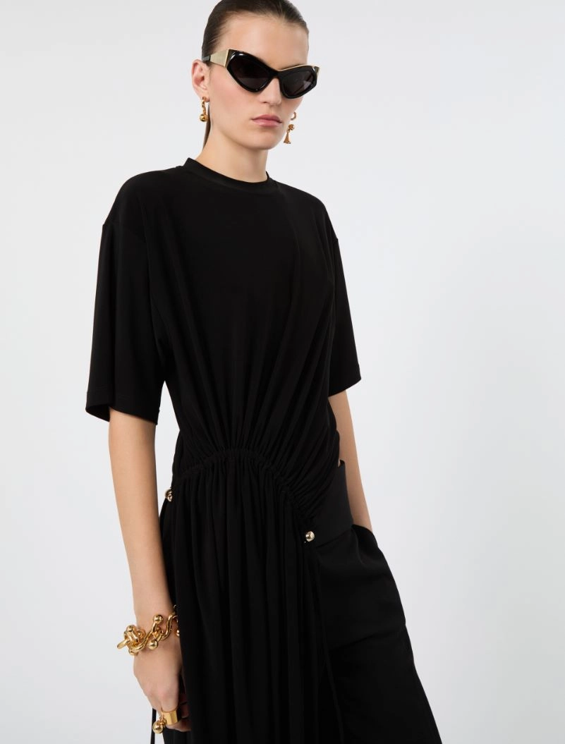IMG_3782 - New Trend Woman in a black, draped dress with a gathered waist, wearing oversized sunglasses and gold jewelry.