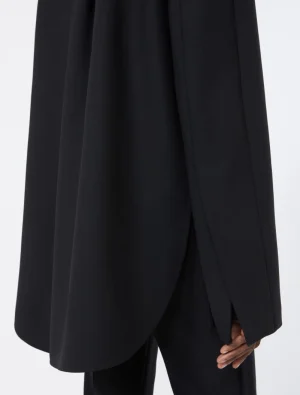 Close-up of a black draped coat or cape with a curved hem and side vent over black pants.