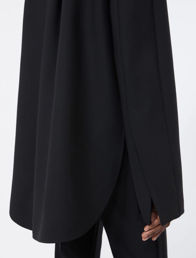 IMG_3800 - New Trend Close-up of a black draped coat or cape with a curved hem and side vent over black pants.