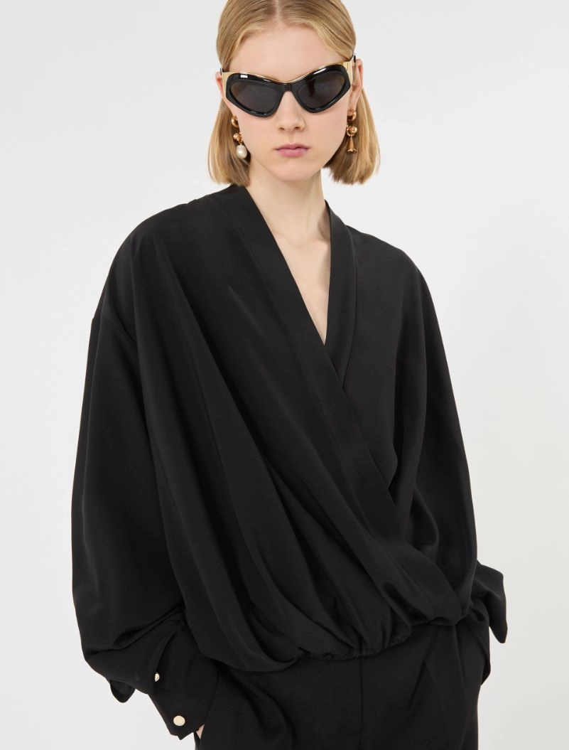 IMG_3805 - New Trend Model wearing a black, draped wrap blouse with oversized sleeves and matching pants, accessorized with large sunglasses and gold earrings.