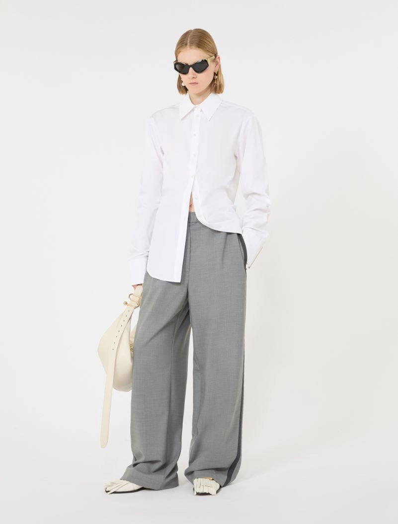 IMG_3807 - New Trend Model wearing an oversized white button-down shirt with gray wide-leg trousers, holding a cream hat and wearing black sunglasses.
