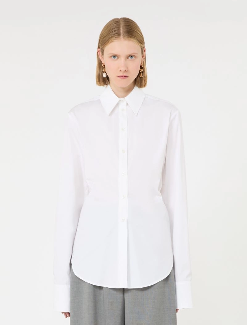 IMG_3808 - New Trend Model wearing a white button-down shirt with long sleeves and a curved hem, paired with gray trousers, facing the camera.