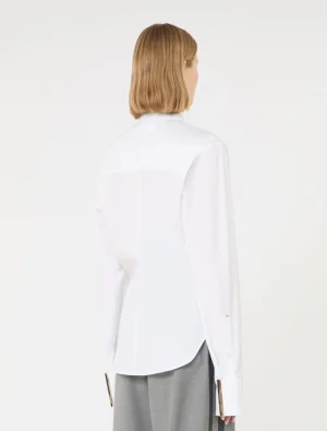 Back view of a person wearing a white button-down shirt with a curved hem and light gray trousers.