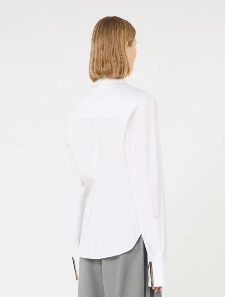 Back view of a person wearing a white button-down shirt with a curved hem and light gray trousers.