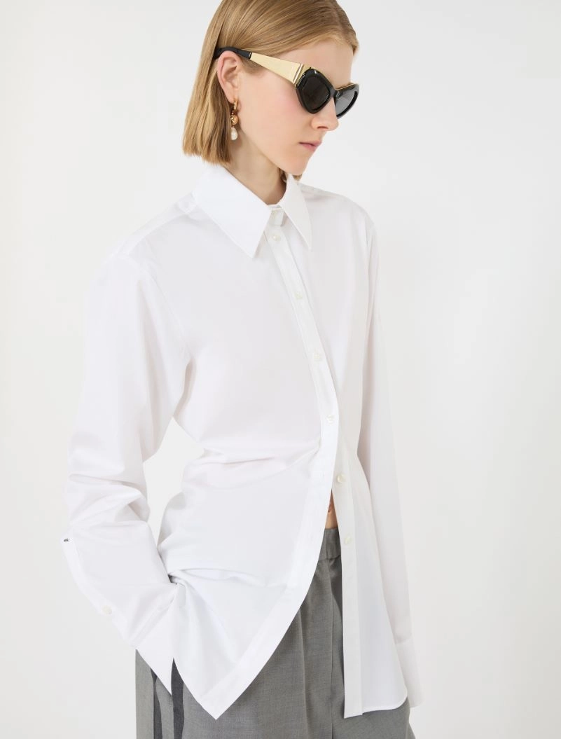 IMG_3810 - New Trend Model wearing an oversized white button-down shirt with gray trousers, sunglasses, and gold earrings in a minimalist studio.