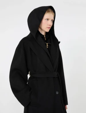 Woman in a black hooded coat with a belt, facing left and gazing forward.