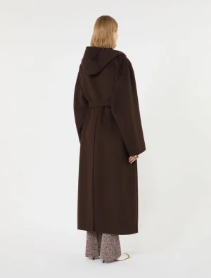 Back view of a person wearing a long brown coat with a belt and hood, standing against a plain white backdrop.