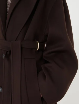 Close-up of a dark brown belted coat with a gold buckle and side pocket detail.