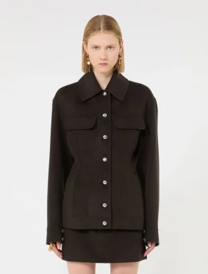 Model wearing a black button-front jacket with two flap pockets and a matching black mini skirt.