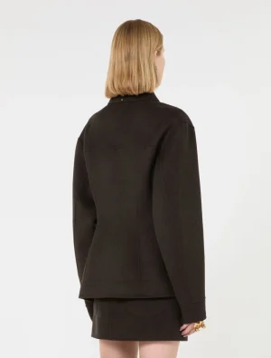 Back view of a person wearing a dark oversized jacket with a matching short skirt, blonde bob hairstyle visible from behind.
