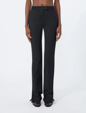 Woman wearing black tailored wide-leg pants with a flat waistband and long legs, paired with dark pointed-toe shoes.