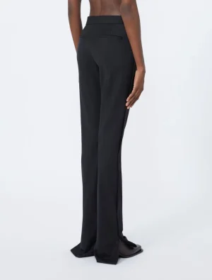 Back view of a person wearing black tailored wide-leg trousers with floor-length hem and back welt pockets