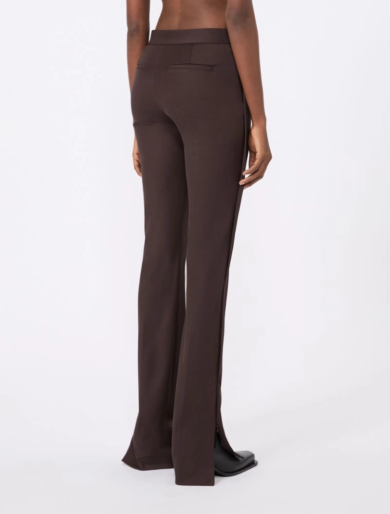IMG_3876 - New Trend Back view of chocolate brown wide-leg trousers on a model, with a flat waistband and rear welt pocket, flaring slightly at the bottom with small side slits.
