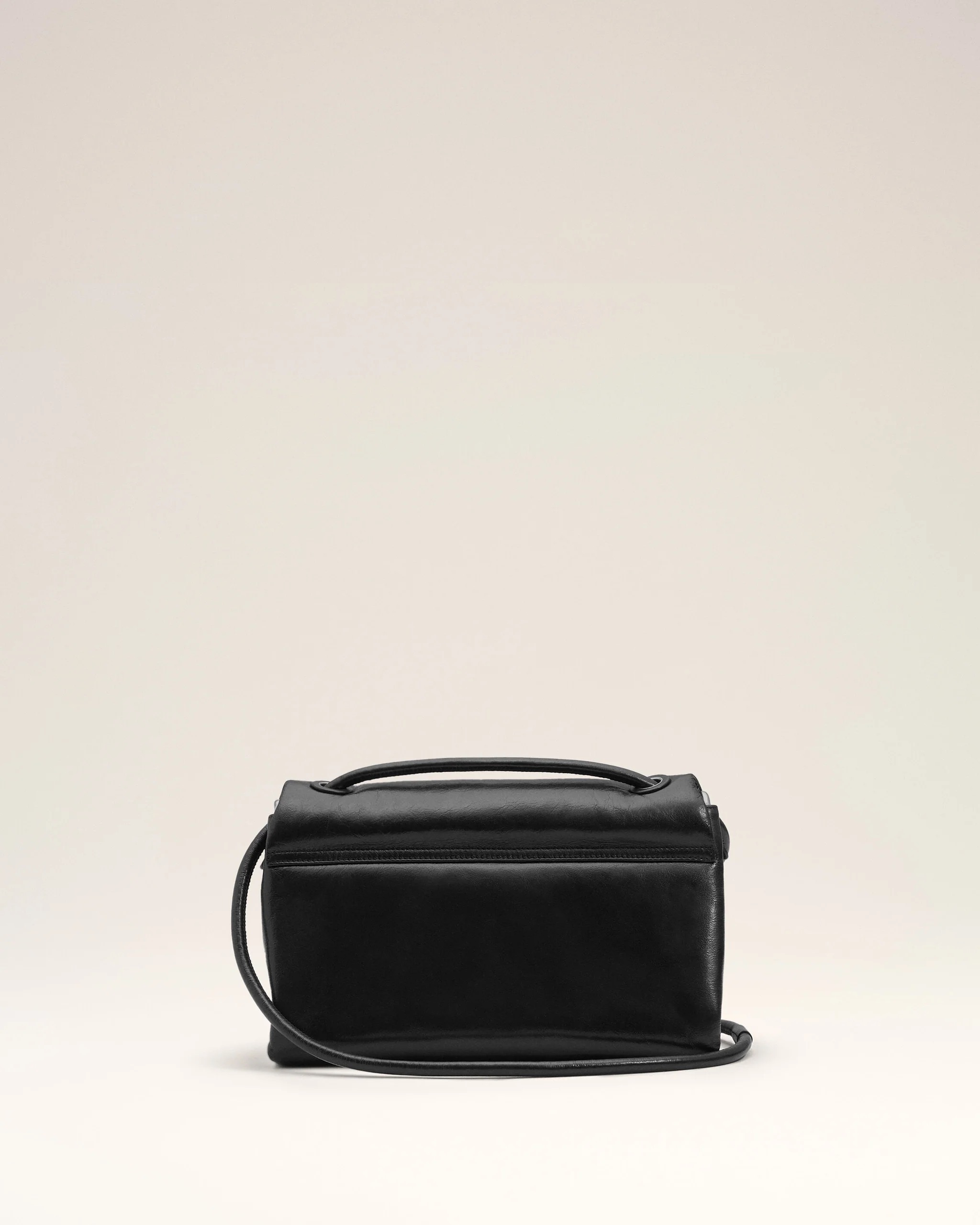 Image 110 - New Trend Black leather handbag with a top handle and long shoulder strap against a pale beige backdrop