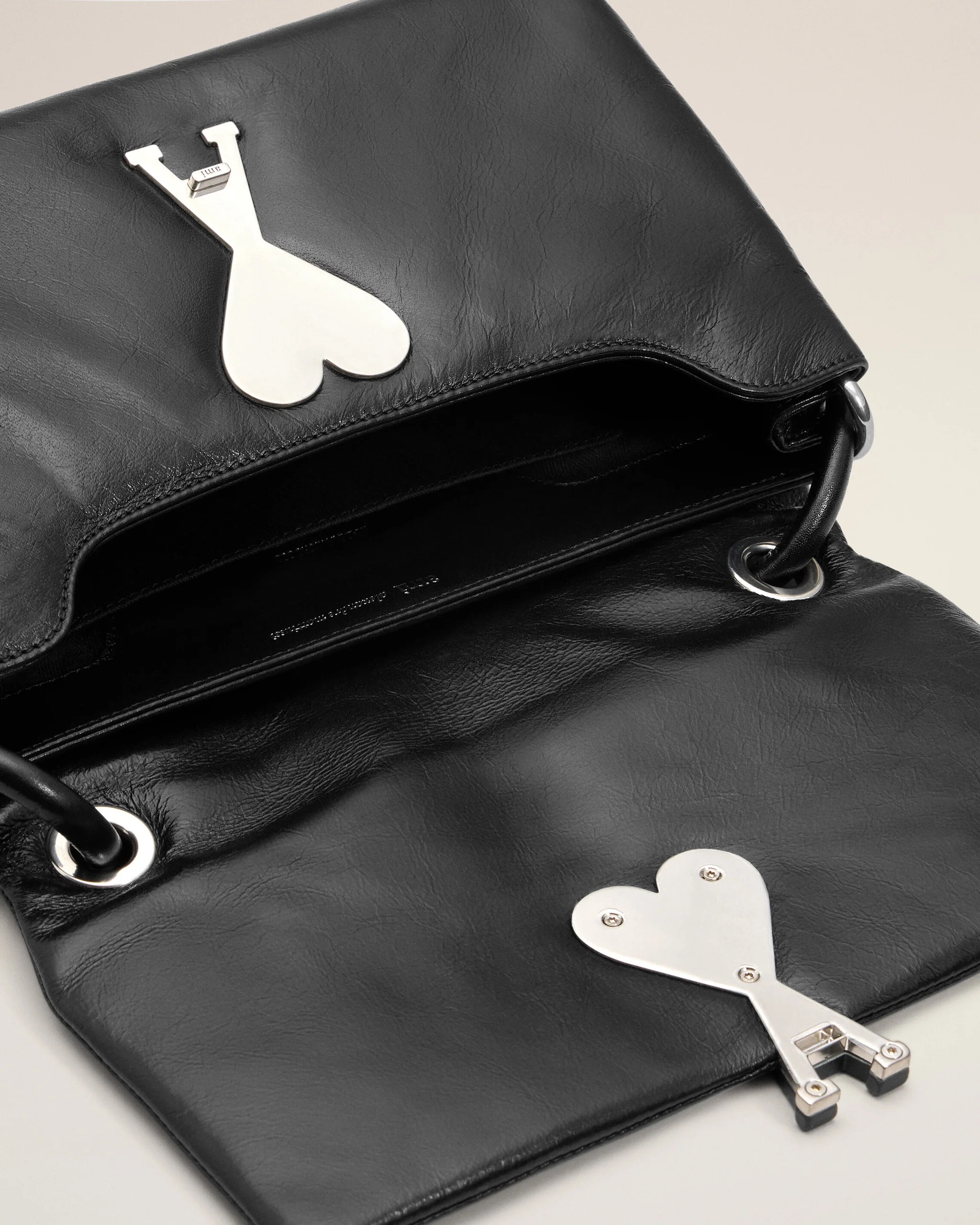 Image 112 - New Trend Close-up of a black leather handbag with a large silver key-shaped ornament featuring a heart-shaped bow on the flap.