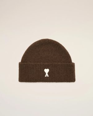 Brown knitted beanie with a small white heart graphic on the front and a folded cuff against a light background.