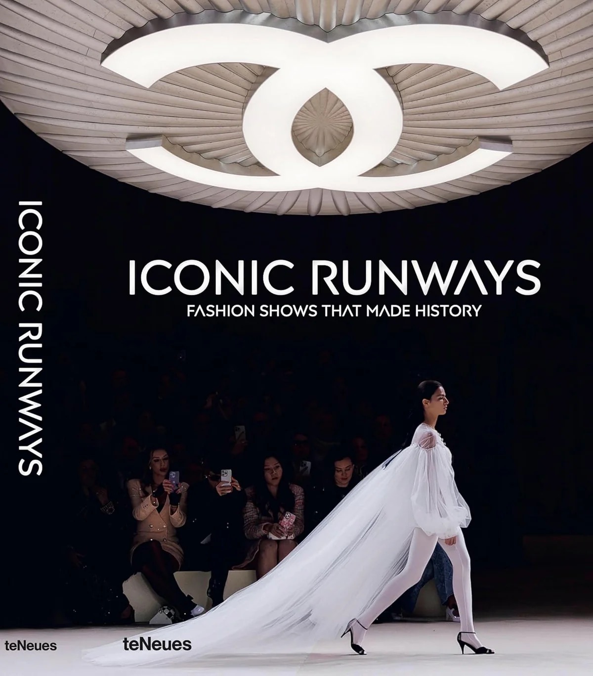 Image 12 - New Trend Poster for Iconic Runways fashion show; a model in a dramatic white gown with a long train walks the runway while the audience watches.