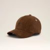 Partial view of a brown corduroy baseball cap with a curved brim against a pale background, the top of the crown shown.