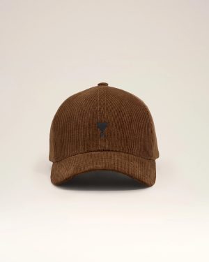 Brown corduroy baseball cap viewed from above with a small dark emblem on the front panel against a pale background,