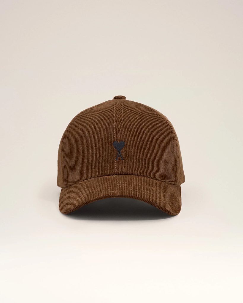 Brown corduroy baseball cap viewed from above with a small dark emblem on the front panel against a pale background,