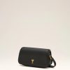 Black leather crossbody bag with a small gold heart clasp on a light beige background.