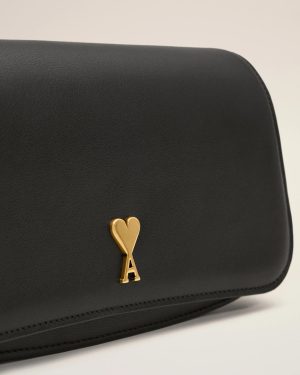 Close-up of a black leather bag with a gold heart-shaped key pendant hanging from it.