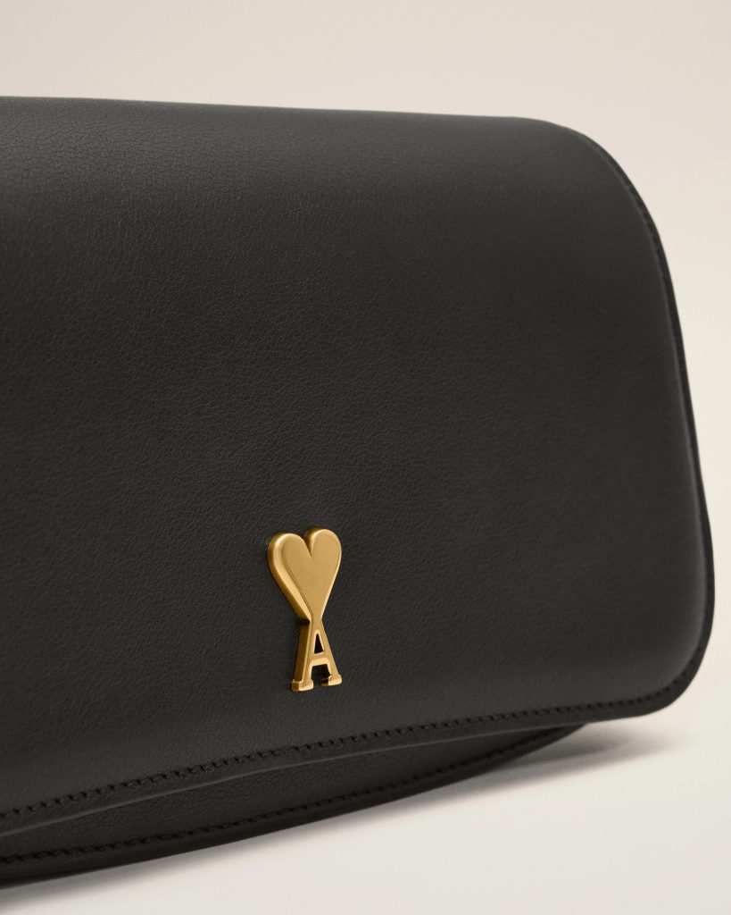 Close-up of a black leather bag with a gold heart-shaped key pendant hanging from it.