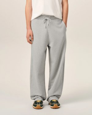 Person wearing light gray sweatpants with a drawstring, white top, and dark green sneakers with gum soles, standing facing forward.