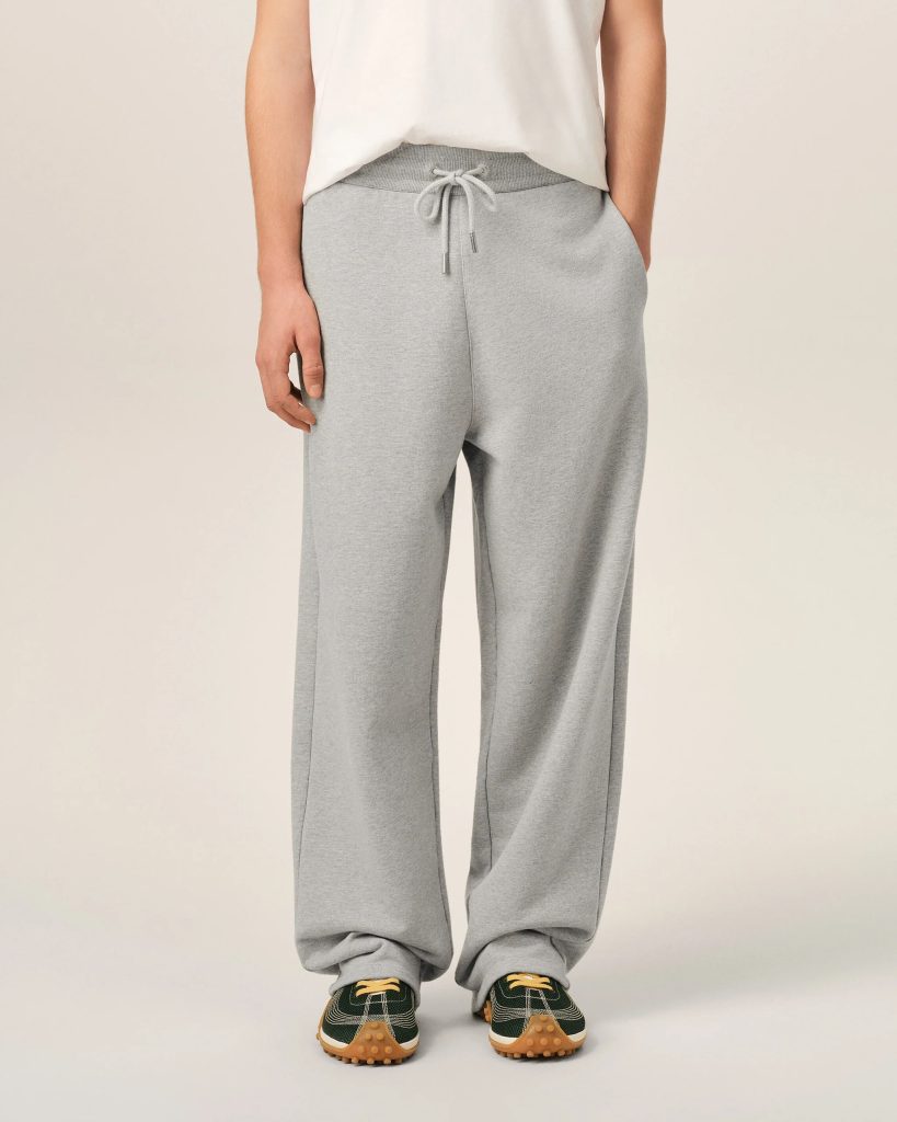 Person wearing light gray sweatpants with a drawstring, white top, and dark green sneakers with gum soles, standing facing forward.