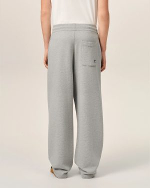 Back view of a person wearing light gray sweatpants with a patch pocket and a small black heart logo on the pocket.