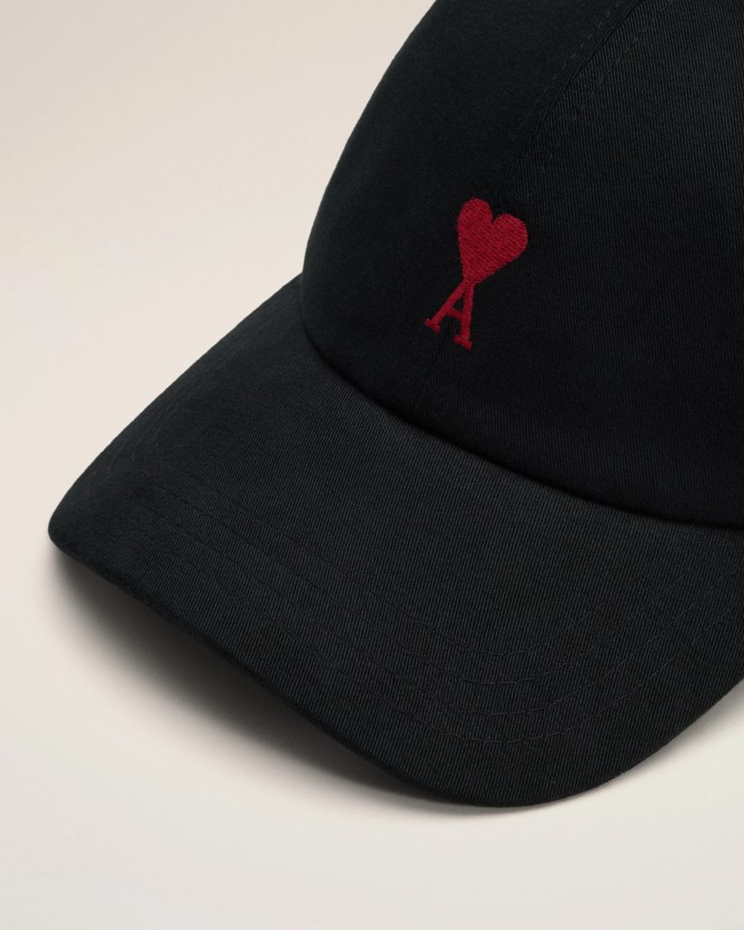 Close-up of a black cap brim with a small red embroidered heart and letter A.