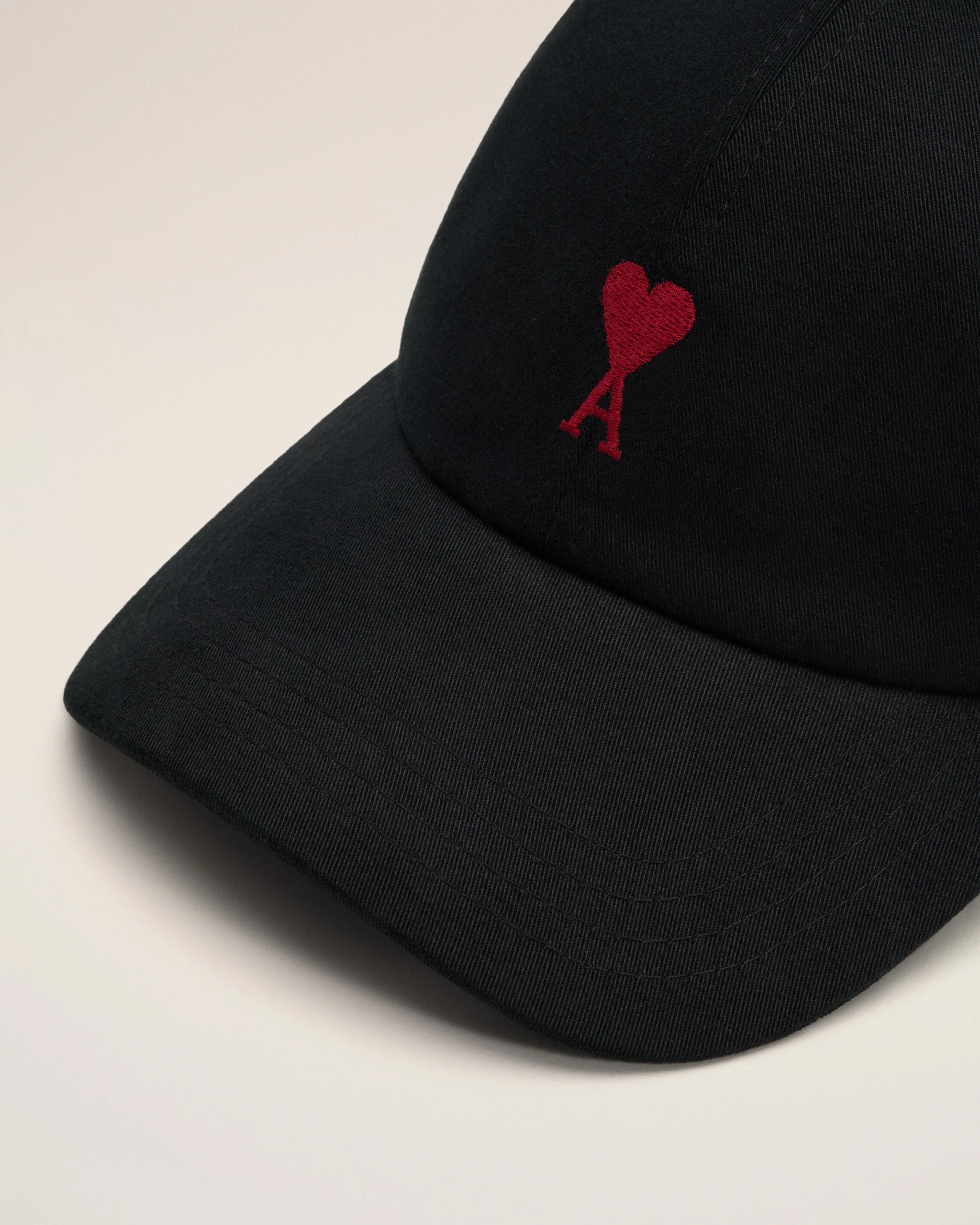 Image 145 - New Trend Close-up of a black cap brim with a small red embroidered heart and letter A.