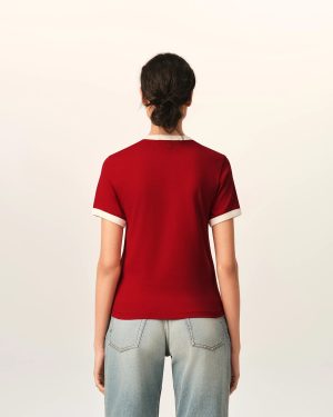 Back view of a person wearing a red short-sleeve shirt with white cuffs and light-blue jeans, standing against a pale background.