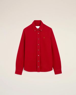 Red button-down shirt with a collar and a small gold logo on the left chest against a beige background.