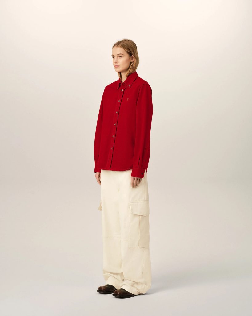 Person model wearing a red button-down shirt and beige cargo pants, standing against a plain light backdrop, facing left in a mid-profile pose.
