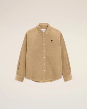 Beige corduroy button-down shirt with white buttons and a small black heart logo on the left chest against a pale background.