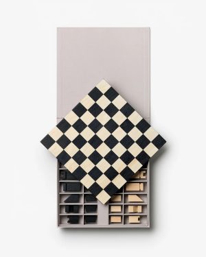 Checkerboard chessboard sits atop an open grey storage box filled with wooden chess pieces and accessories in individual compartments, viewed from above.