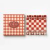 Red-and-white decorative chess set: a checkered board with matching patterned box beside it (chess pieces on board).